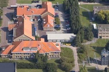 <p>Het tijdelijke bureelgebouw uit 1947 (met grijze dakbedekking) op een relatief recente luchtfoto van de Elias Beeckmankazerne. </p>
